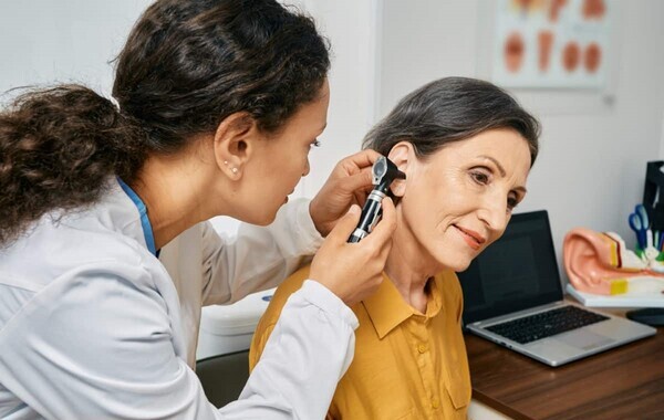 Feature image of a doctor checking ears with an otoscope. Advantages of Addressing Hearing Impairment